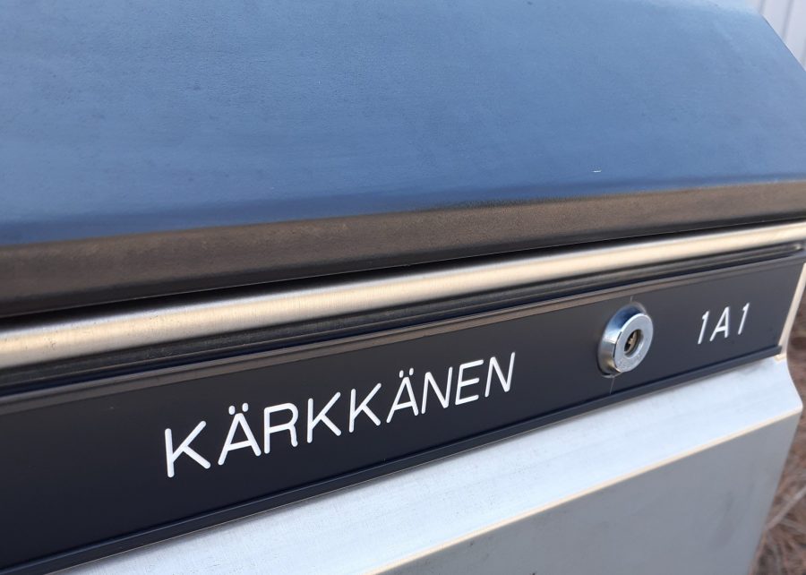 Mustalle pohjalle kaiverrettu nimikyltti postilaatikkoon