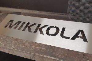 Nimikyltti taloon. Materiaali ruostumaton teräs, nimi aukileikattu.